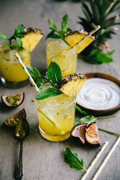 two glasses filled with lemonade and mint garnish on top of a table