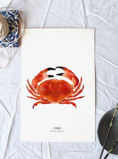 a card with an image of a crab on it next to some thread and scissors