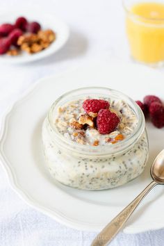 a bowl of oatmeal with raspberries and nuts on the side