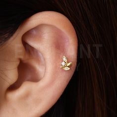 a woman's ear with two small gold leaves on it