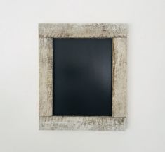 an old wooden frame with a chalkboard in the middle on a white wall behind it