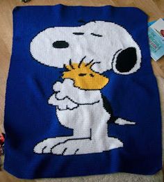 a cross - stitch snoopy blanket is laying on the floor