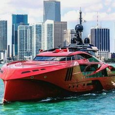 a large red boat is in the water near some tall buildings and skyscrapers behind it