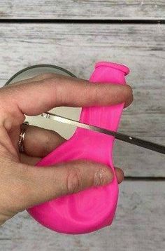 a person is cutting something with a pair of scissors and pink plastic object in front of them