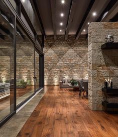 a living room with wood floors and stone walls is lit up by recessed lights