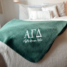 a bed with a green blanket on top of it and the letters ata written in white