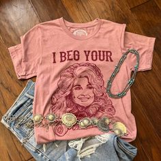 I Beg Your Parton Tee, Dolly Parton T-Shirt. You don't have this tee yet? I beg your...?! Our best-selling tee of all time, featuring the one and only queen Dolly. It is on a heather orchid tee that is lightweight, stretchy, and a true-to-size unisex fit and the design is a screen print, so won't fade or peel after washing. 52% cotton 48% polyester Best Selling T Shirt, Western Boutique Clothing, Graphic Tees Western, Dolly Parton T Shirt, Cactus Rose, Fashion Trends Summer, Western Tee, Cowgirl Fashion, Western Boutique