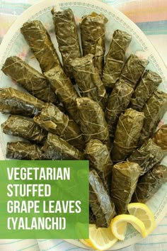 there are grape leaves wrapped in paper on the plate with lemon wedges next to it