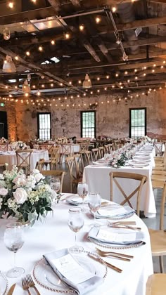 tables set up for an event with white linens and gold place settings