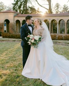 a bride and groom standing in front of an old building at sunset with the sun shining on them