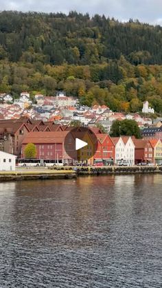 a town on the water with houses and mountains in the background