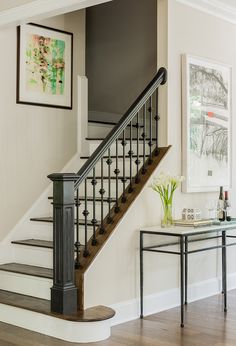 an image of a staircase and table in the living room with pictures on the wall