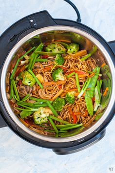 a pot filled with noodles, broccoli and carrots