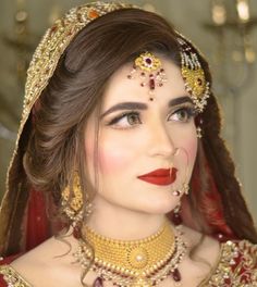 a woman wearing a red and gold bridal outfit