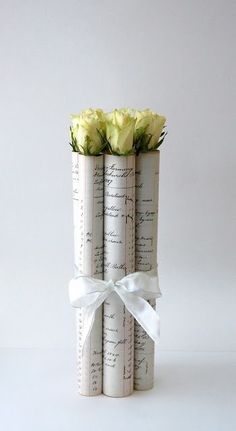 three rolled up books with flowers in them