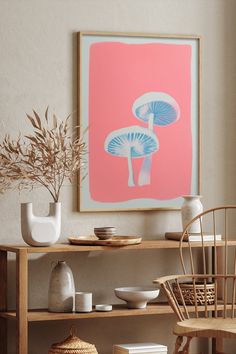 a table with vases and plates on it in front of a framed mushroom print