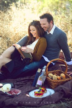 a man and woman sitting on a blanket with food