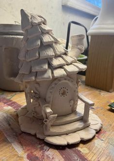 a clay house sitting on top of a wooden table