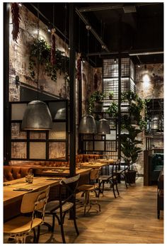 an empty restaurant with wooden tables and green couches, hanging plants and potted plants