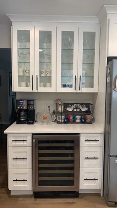 a kitchen with white cabinets and stainless steel appliances, including a wine cooler in the center