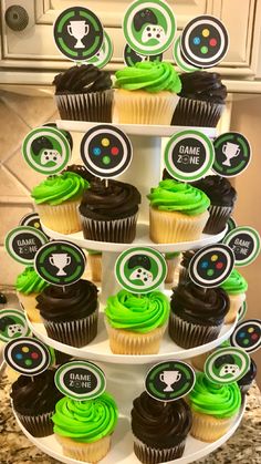 cupcakes are stacked on top of each other with green frosting and black icing