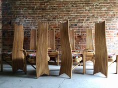 a group of wooden chairs sitting next to each other in front of a brick wall