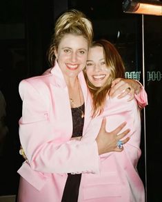 two women hugging each other in front of a mirror