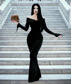 a woman in a black dress holding a donut and posing for the camera on some steps