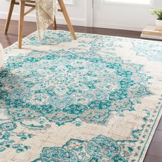 a blue and white area rug with an ornate design on the bottom, in front of a window