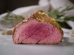 a piece of meat sitting on top of a white plate next to garlic and herbs