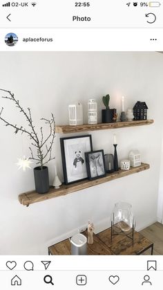 two wooden shelves with pictures and candles on them in a room that has white walls