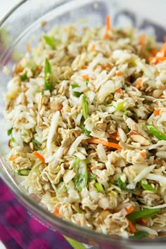 a bowl filled with rice and vegetables on top of a colorful table cloth next to a fork