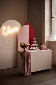 a table topped with lots of cake next to a neon sign