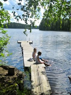 two children are sitting on a dock by the water