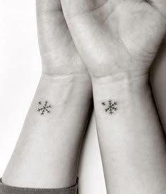 two wrist tattoos with small snowflakes on them