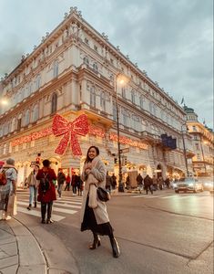 a woman standing in front of a large building with christmas decorations on it's side