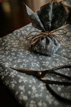 a pair of scissors sitting on top of a blue table cloth covered in black and white flowers