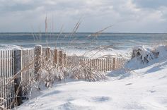 the snow is covering the beach and fence