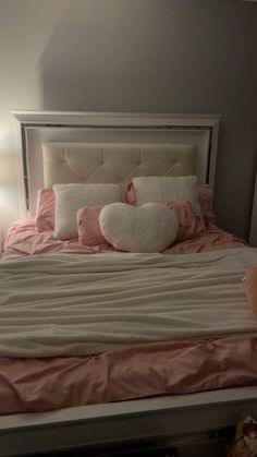 a bed with pink and white pillows on top of it next to a night stand