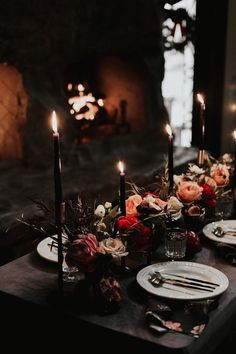 the table is set with candles and flowers on it, along with other place settings