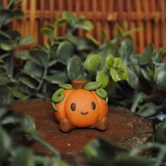 a small toy pumpkin sitting on top of a tree stump in front of some plants