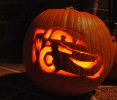 two carved pumpkins sitting on top of a table next to each other, one with an image of a car