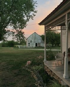 an old white house sitting on top of a lush green field next to a tree