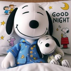 a snoopy stuffed animal sitting on top of a bed next to a pillow with the words good night written on it