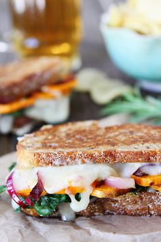 a grilled sandwich with cheese, meat and veggies sits on a piece of parchment paper