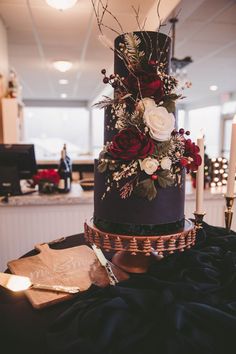 a black and gold wedding cake with flowers on it