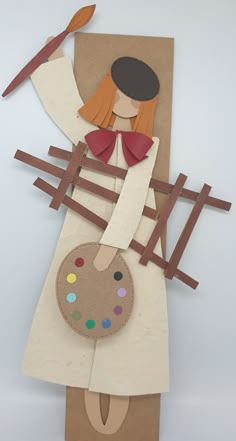 an art project made out of cardboard and paper with a woman holding paintbrushes