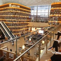 people are sitting on the stairs in a library with many bookshelves full of books