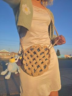 a woman is holding a crocheted purse on her shoulder and posing for the camera