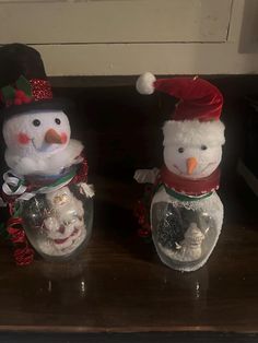 three snowmen in hats and scarfs sitting on a table